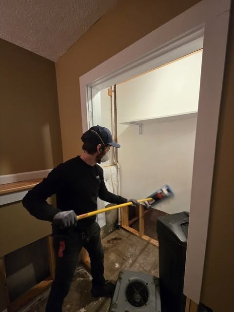 A Remont crew member removing damaged drywall