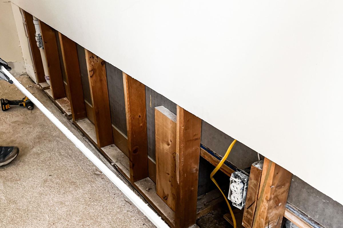 Wet drywall cut away along the bottom of a wall so the framing can dry